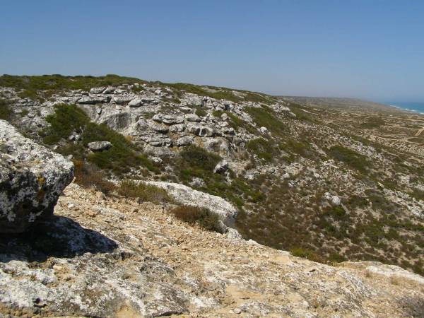 Rocky hillsides lead down to  | the Great Australian Bight,  | Nullarbor Plain,  | Eyre Highway,  | South Australia  | 